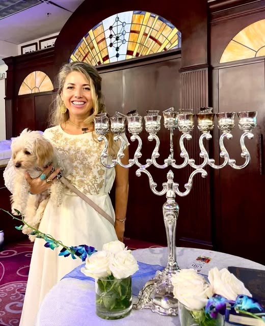 Dashama holding Amore beside a large silver menorah